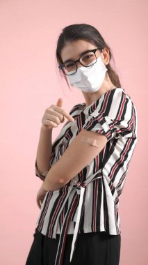 Genç kadın COVID-19 aşısını neşeyle sargılıyor.