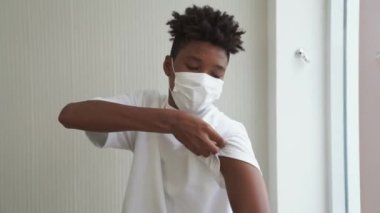 Afro-Amerikalı genç COVID-19 aşısını neşeyle gösteriyor.
