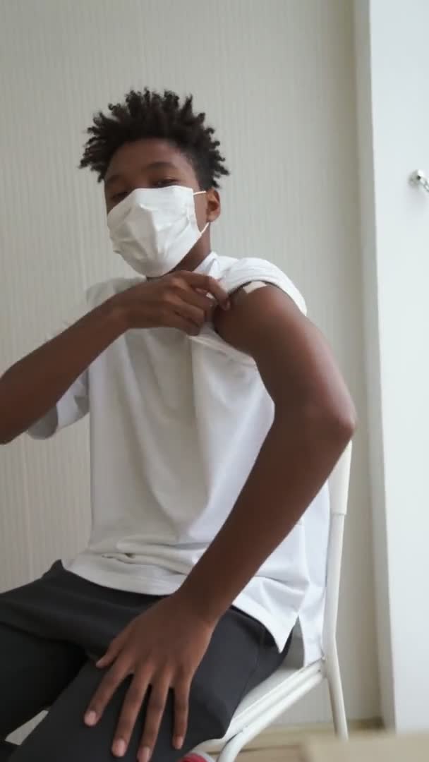 Pionowe wideo afrykańskiego nastolatka pokazujące bandaż szczepionkowy COVID-19 wesoło — Wideo stockowe