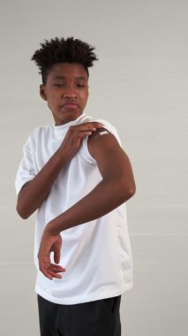 Afrikalı bir gencin dikey videosu COVID-19 aşı bandajını neşeyle gösteriyor.