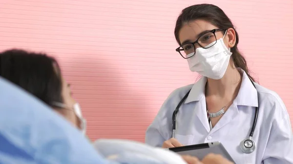Doctor wearing face mask proficiently talks with patient at hospital ward — Stock Photo, Image