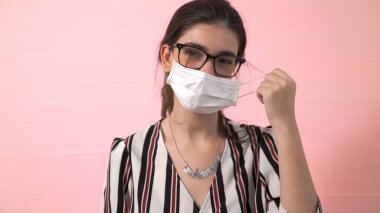 Genç bir kadın yüzünden maskesini çıkarıyor.