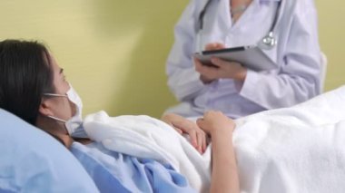 Yüz maskesi takan doktor hastane koğuşundaki hastalarla düzgün bir şekilde konuşuyor.