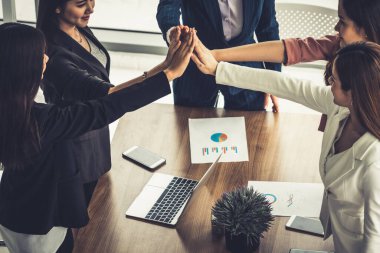 Takım çalışanı kadınlar toplantıda el ele tutuşuyor.