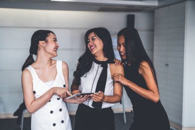 Üç kadın arkadaş tablet bilgisayarla sohbet ediyor.