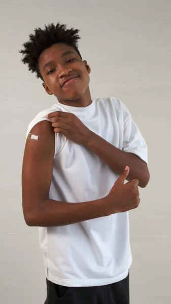 Adolescente afroamericano mostrando alegremente vendaje de vacuna COVID-19 — Foto de Stock