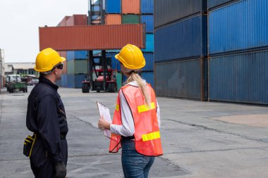 Endüstriyel işçiler, deniz aşırı nakliye konteynır sahasında iş arkadaşlarıyla çalışıyor.