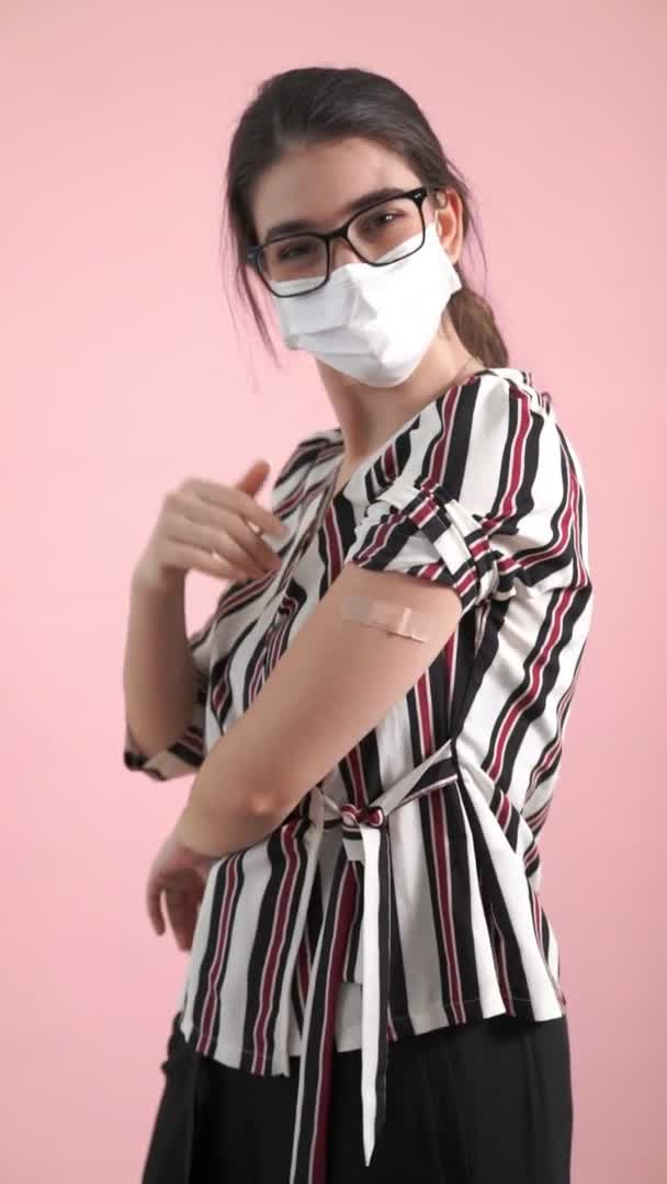 COVID-19ワクチン包帯を示す若い女性の垂直ビデオ — ストック動画
