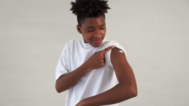African American teenager showing COVID-19 vaccine bandage merrily — Stock Video