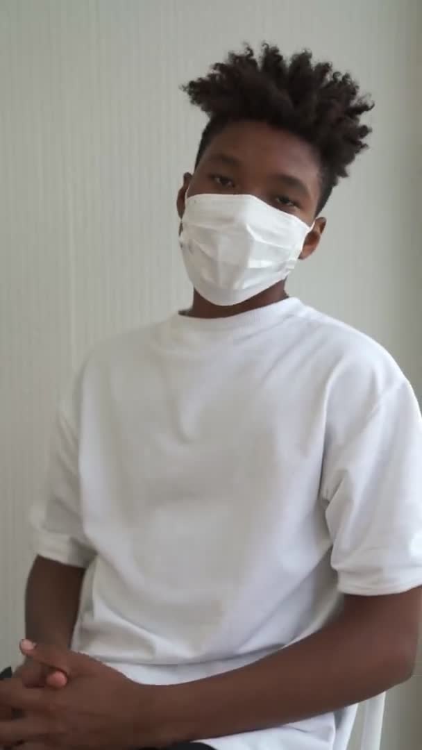 Вертикальное видео молодого африканца снимающего маску с лица — стоковое видео