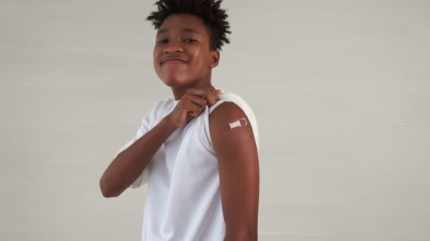 Adolescente afroamericano mostrando alegremente vendaje de vacuna COVID-19 — Vídeos de Stock