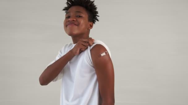 African American nastolatek pokazując COVID-19 szczepionka bandaż wesoło — Wideo stockowe