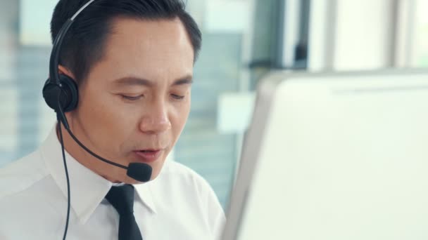 Homem de negócios usando fone de ouvido trabalhando ativamente no escritório — Vídeo de Stock