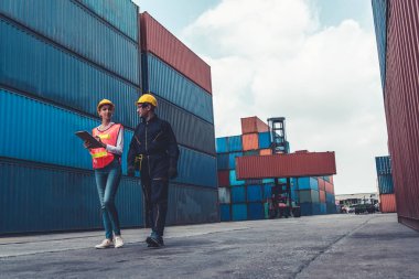 Endüstriyel işçiler, deniz aşırı nakliye konteynır sahasında iş arkadaşlarıyla çalışıyor.