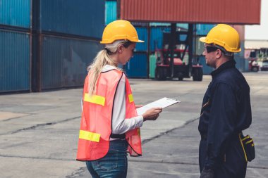 Endüstriyel işçiler, deniz aşırı nakliye konteynır sahasında iş arkadaşlarıyla çalışıyor.