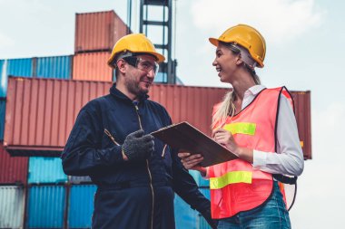 Endüstriyel işçiler, deniz aşırı nakliye konteynır sahasında iş arkadaşlarıyla çalışıyor.