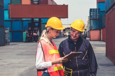 Endüstriyel işçiler, deniz aşırı nakliye konteynır sahasında iş arkadaşlarıyla çalışıyor.