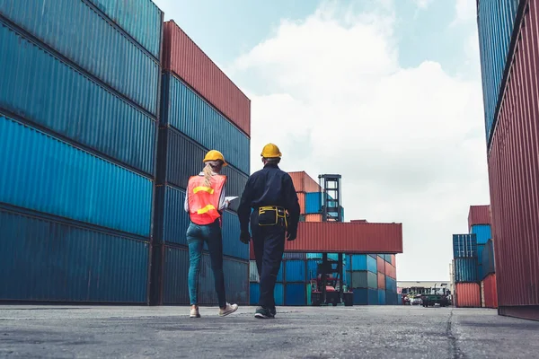 Trabajador industrial trabaja con su compañero de trabajo en el patio de contenedores de envío en el extranjero — Foto de Stock