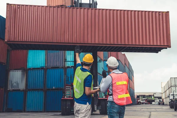 Trabajador industrial trabaja con su compañero de trabajo en el patio de contenedores de envío en el extranjero — Foto de Stock