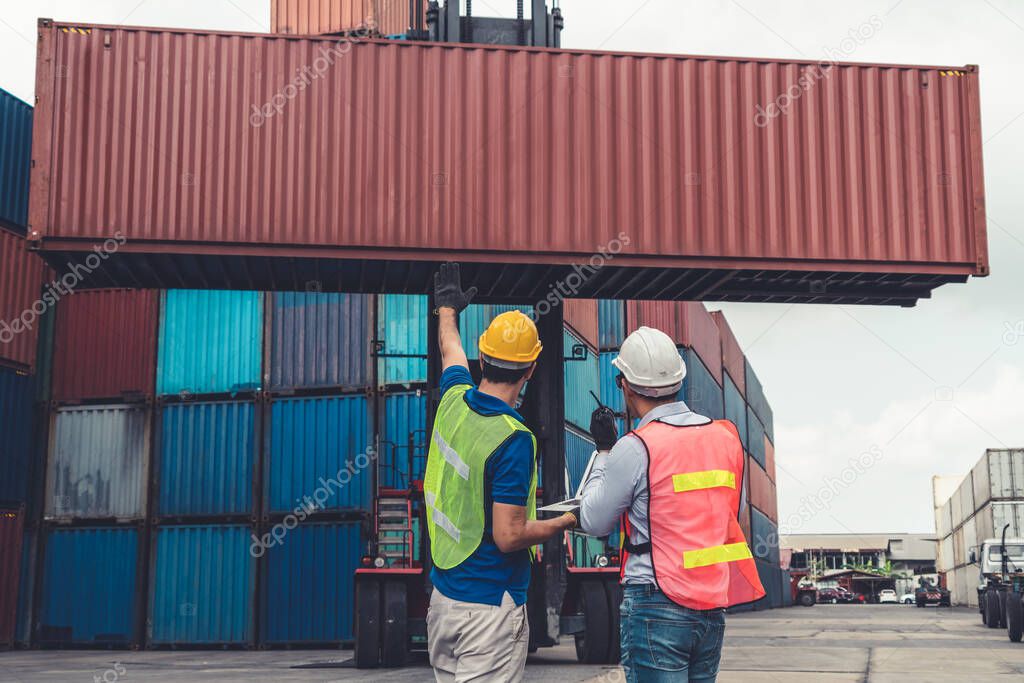 Industrial worker works with co-worker at overseas shipping container yard