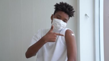 Afro-Amerikalı genç COVID-19 aşısını neşeyle gösteriyor.