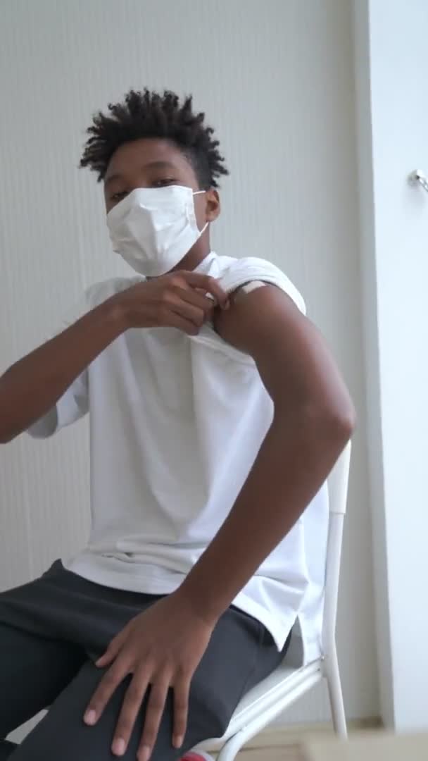 Vertikal video med afrikansk tonåring som visar COVID-19 vaccinbandage glatt — Stockvideo