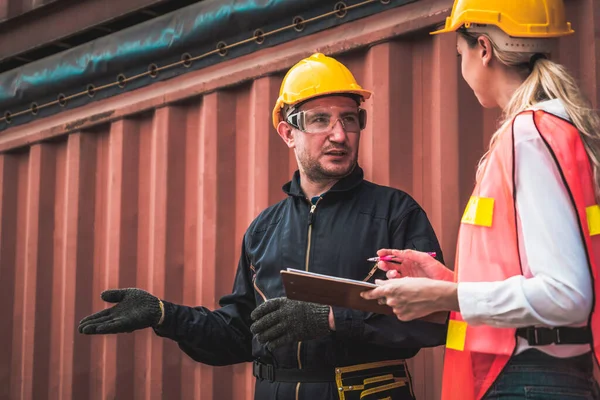 Industrial worker works with co-worker at overseas shipping container yard