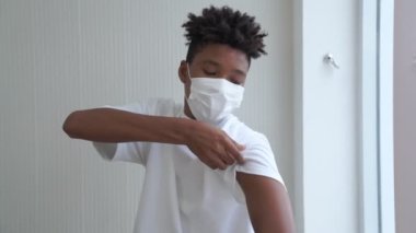 Afro-Amerikalı genç COVID-19 aşısını neşeyle gösteriyor.