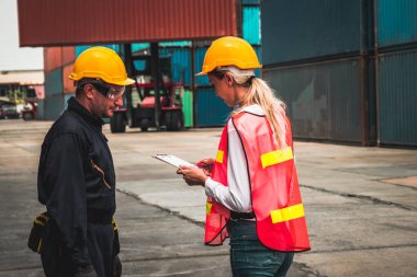 Endüstriyel işçiler, deniz aşırı nakliye konteynır sahasında iş arkadaşlarıyla çalışıyor.