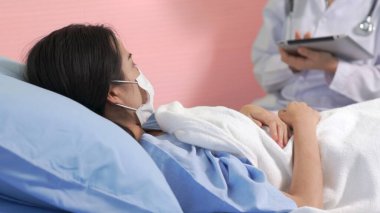 Yüz maskesi takan doktor hastane koğuşundaki hastalarla düzgün bir şekilde konuşuyor.