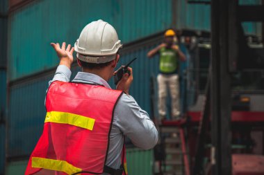 Endüstriyel işçiler, deniz aşırı nakliye konteynır sahasında iş arkadaşlarıyla çalışıyor.