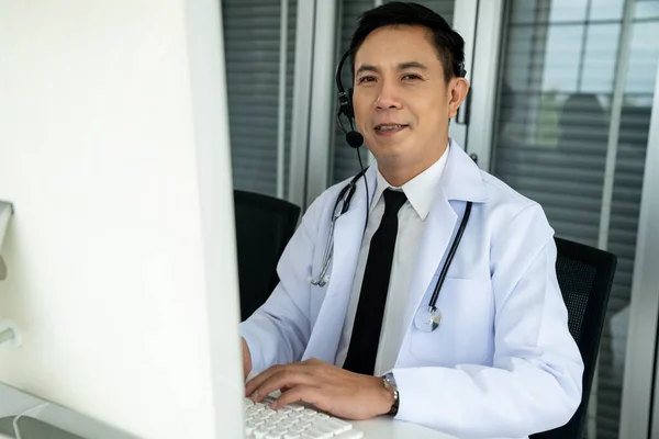 Orvos visel headset beszél aktívan videohívás egy klinikán vagy kórházban . — Stock Fotó
