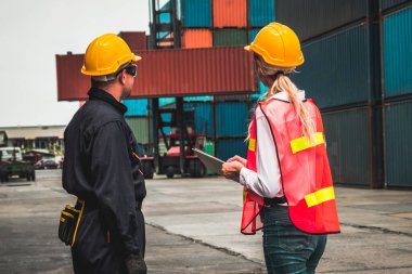 Endüstriyel işçiler, deniz aşırı nakliye konteynır sahasında iş arkadaşlarıyla çalışıyor.