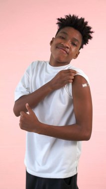 Afro-Amerikalı genç COVID-19 aşısını neşeyle gösteriyor.