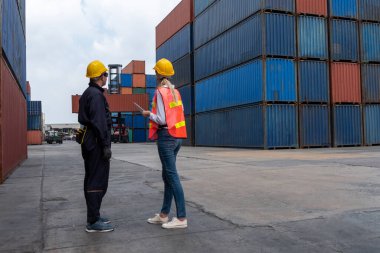 Endüstriyel işçiler, deniz aşırı nakliye konteynır sahasında iş arkadaşlarıyla çalışıyor.