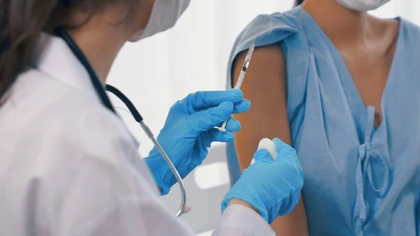 Young woman visits skillful doctor at hospital for vaccination