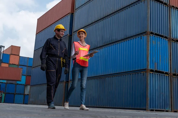 Industrial worker works with co-worker at overseas shipping container yard