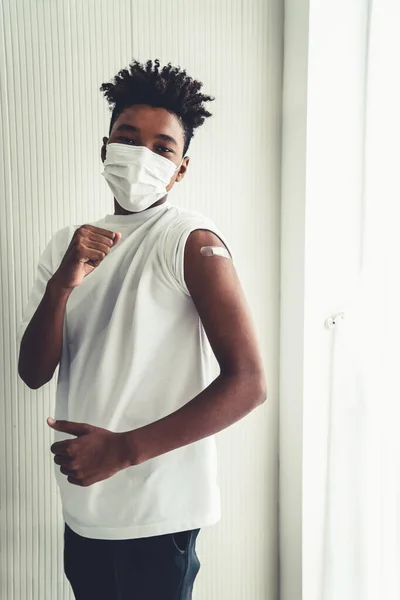 African American nastolatek pokazując COVID-19 szczepionka bandaż wesoło — Zdjęcie stockowe