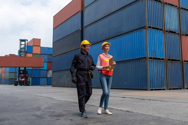 Industrial worker works with co-worker at overseas shipping container yard