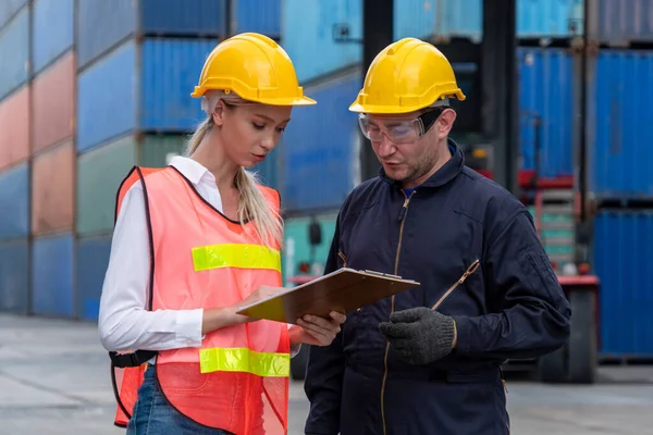 Industrial worker works with co-worker at overseas shipping container yard