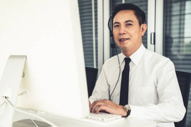 Kulaklık takan bir işadamı aktif olarak ofiste çalışıyor.