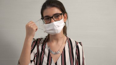 Genç bir kadın yüzünden maskesini çıkarıyor.