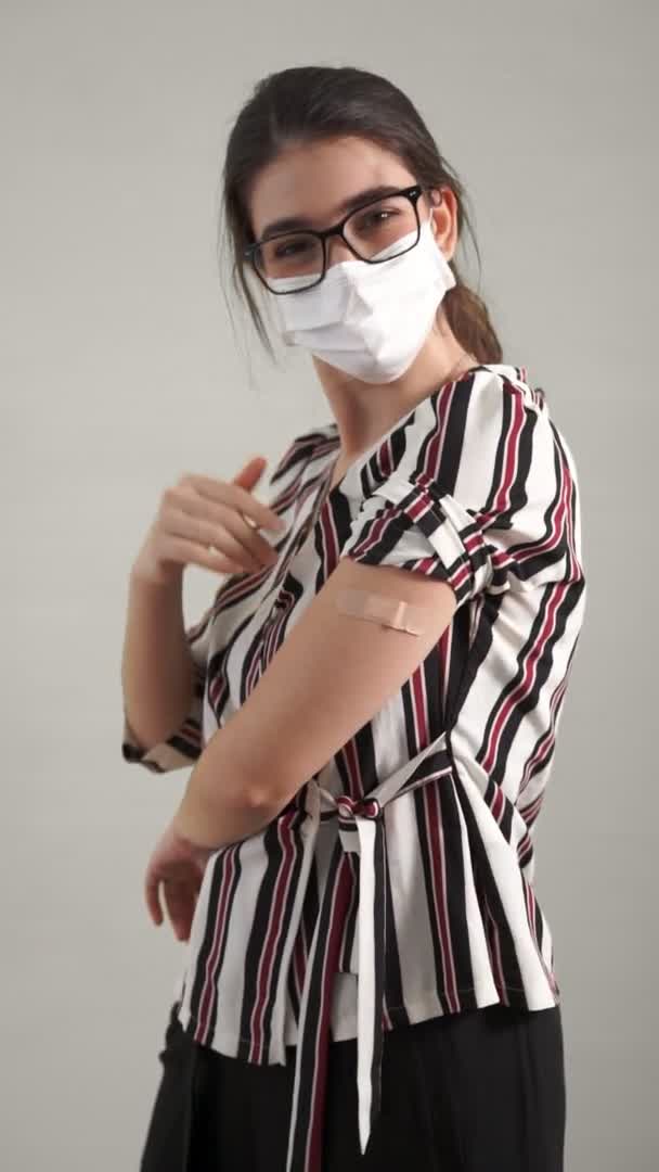 Video verticale di una giovane donna che mostra allegramente la fasciatura del vaccino COVID-19 — Video Stock