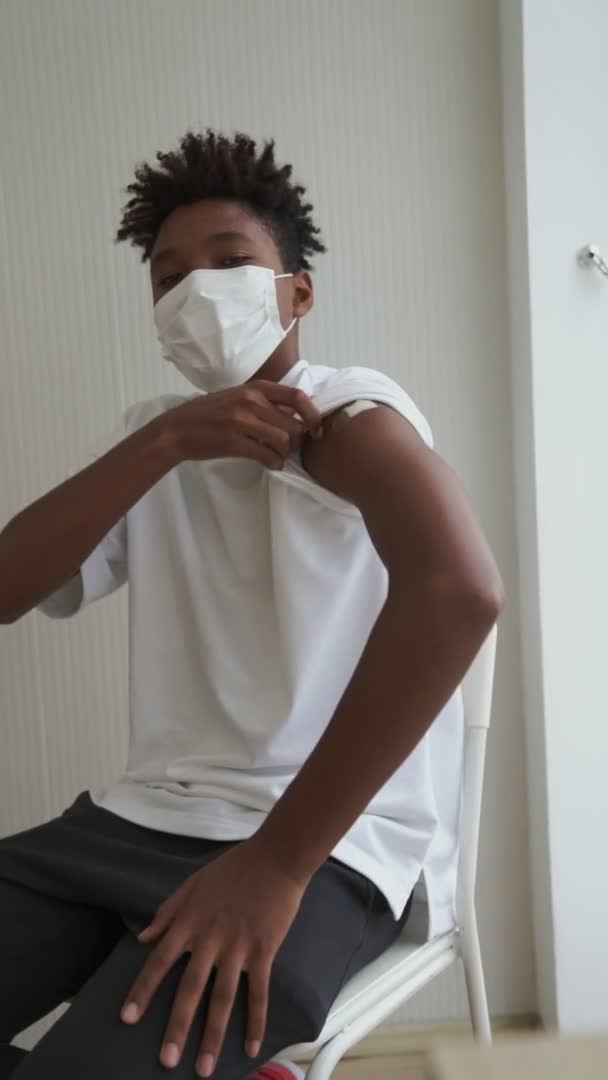 Vertical video of African teenager showing COVID-19 vaccine bandage merrily — Stock Video