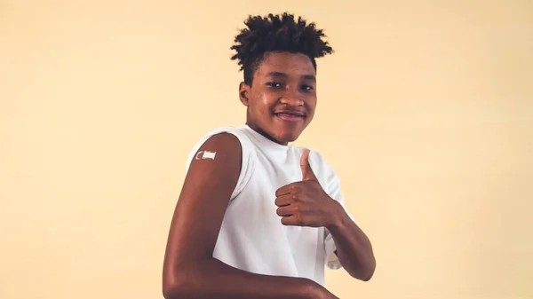 Adolescente afroamericano mostrando alegremente vendaje de vacuna COVID-19 — Foto de Stock