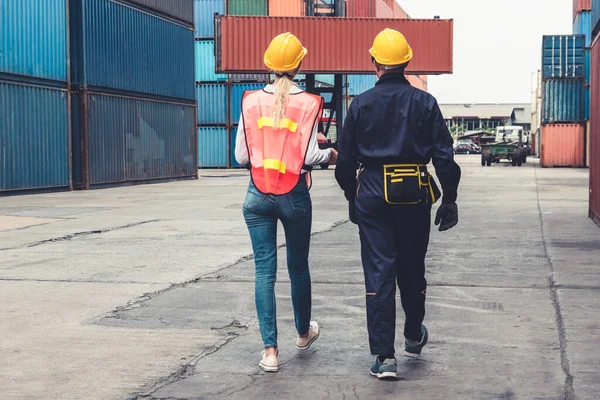 Industrial worker works with co-worker at overseas shipping container yard