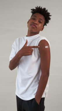 Afrikalı bir gencin dikey videosu COVID-19 aşı bandajını neşeyle gösteriyor.