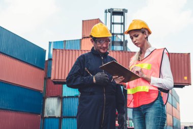 Endüstriyel işçiler, deniz aşırı nakliye konteynır sahasında iş arkadaşlarıyla çalışıyor.