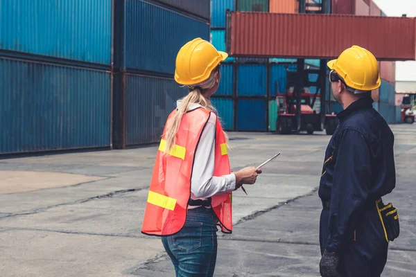 Endüstriyel işçiler, deniz aşırı nakliye konteynır sahasında iş arkadaşlarıyla çalışıyor.