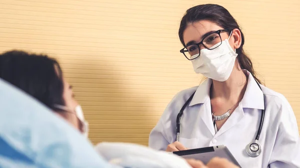 Doctor wearing face mask proficiently talks with patient at hospital ward — Stock Photo, Image